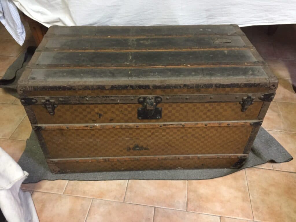 Tasación de precio para un baúl Louis Vuitton numerado, dañado y agrietado en la parte superior, considerado para una subasta