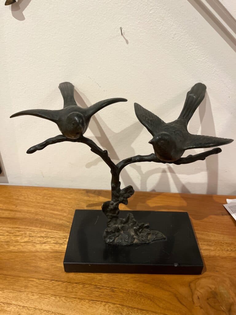 Estatua de aves sobre rama con base de mármol negro